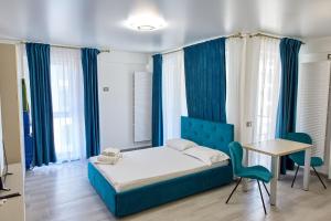 1 dormitorio con cama, mesa y cortinas azules en Studio Melody Nord 10, en Năvodari