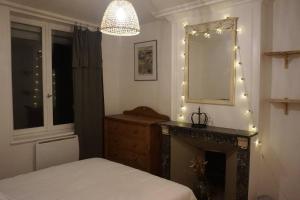 1 dormitorio con cama, espejo y chimenea en Suites Carnot, Venise Normande., en Pont-Audemer