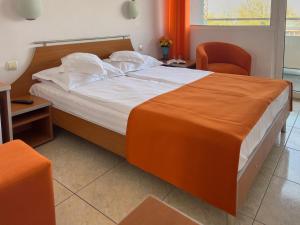 a bedroom with a large bed and a chair at HOTEL DUNĂREA in Mamaia
