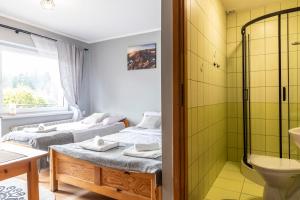 two beds in a room with a shower and a bathroom at Pensjonat Góraleczka-Kościelisko in Kościelisko