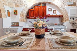 uma cozinha com uma mesa com pratos e copos de vinho em Il trullo felice em Locorotondo