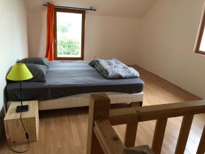 ein Schlafzimmer mit einem Bett mit gelber Lampe und einem Fenster in der Unterkunft Petite maison spacieuse in Billy