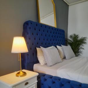 uma cama com uma cabeceira azul e uma mesa com um candeeiro em Airplane Residence 1 em Otopeni