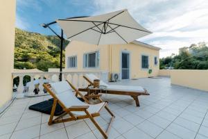 a patio with two chairs and an umbrella at Corfu Stinados Apartment in Giannádes