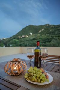 a table with two glasses of wine and a plate of grapes at Corfu Stinados Apartment in Giannádes
