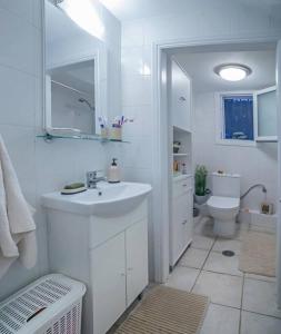 a white bathroom with a sink and a toilet at Corfu Stinados Apartment in Giannádes