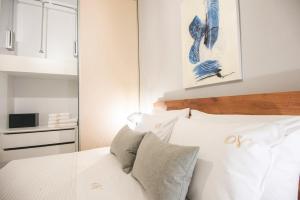 1 dormitorio con cama blanca y almohadas blancas en Nicolas Exclusive Apartment, en Agios Nikolaos