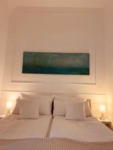 Una cama con almohadas blancas y una pintura encima. en Apartment 229, en Dortmund