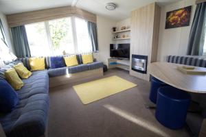 Una sala de estar con un sofá azul y una mesa. en Caravan With Decking Within Walking Distance To Hunstanton Beach Ref 23054S, en Hunstanton