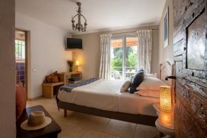 a bedroom with a bed and a large window at Hotel Les Messugues in Saint Paul de Vence +86 photos