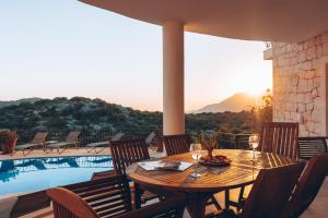 a wooden table and chairs next to a swimming pool at Hill House Adult Only in Kaş