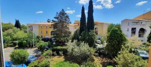 a garden in front of a building with cypress trees at Studio 4 personnes au Cap-d'Agde in Agde
