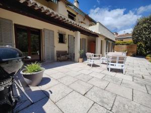 een patio met witte stoelen en een tafel bij Bas de villa indépendant. 10min de la mer in Biot