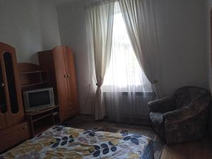 een slaapkamer met een bed, een stoel en een raam bij Апартаменти 15 хв від жд вокзалу in Lviv