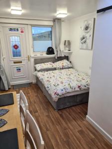 a bedroom with a bed and a table and a window at Sunset Place in Lower Boscaswell