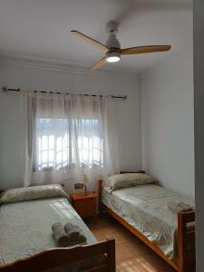 1 dormitorio con 2 camas y ventilador de techo en Chalet Santi Playa de la Barrosa, en Chiclana de la Frontera