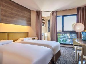 una camera d'albergo con due letti e una finestra di AppartHotel Mercure Paris Boulogne a Boulogne-Billancourt