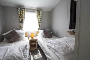 a small room with two beds and a window at Beautiful 6 Berth Caravan At Southview Holiday Park In Skegness Ref 33031s in Skegness