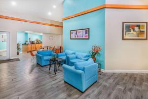 a waiting room with blue chairs and a table at Howard Johnson by Wyndham Houston Hobby in Houston