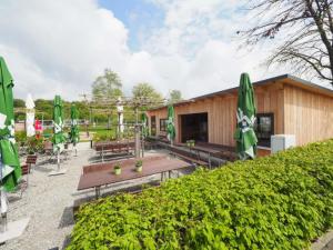 un patio con mesas de picnic y sombrillas verdes en Holzhütte I21 groß en Reichenau