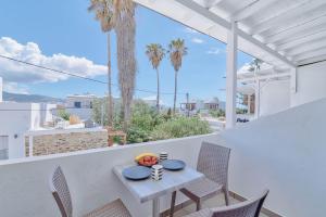 Una mesa y sillas en un balcón con palmeras. en Pavlos Place, en Antíparos