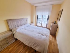 sypialnia z białym łóżkiem i oknem w obiekcie Portosín -Suites w mieście Portosin