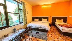 two beds in a room with orange walls and windows at Mountain Vista in Dharamshala