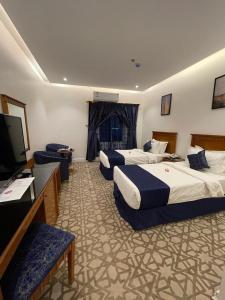 a hotel room with three beds and a flat screen tv at Al Farhan Hotel & Suites Hafr Al Batin in Abū Qa‘ar