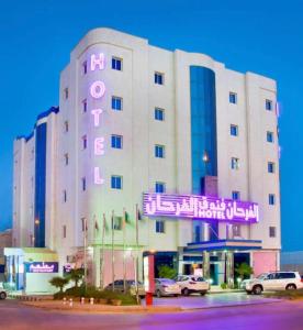 a large white building with a neon sign on it at Al Farhan Hotel & Suites Hafr Al Batin in Abū Qa‘ar