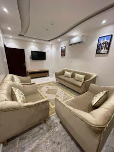 a living room with couches and a flat screen tv at Al Farhan Hotel & Suites Hafr Al Batin in Abū Qa‘ar