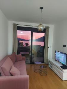 ein Wohnzimmer mit einem rosa Sofa und einem großen Fenster in der Unterkunft Видовые апартаменты в здании Manor in Tivat