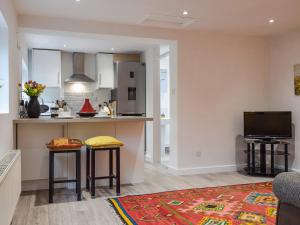 a kitchen and living room with two stools and a counter at The Stables in Long Itchington