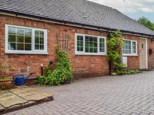 a brick house with white windows and a brick driveway at The Stables in Long Itchington