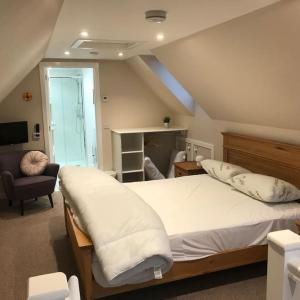 a bedroom with a large white bed and a chair at Westmains Lodge in Callander