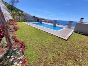 a backyard with a swimming pool next to the ocean at Stunning Lobos View in Câmara de Lobos