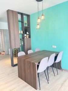 comedor con mesa de madera y sillas blancas en Emerald Avenue Cozy 3R3B Apartment 716, en Brinchang