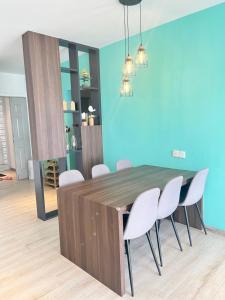 ein Esszimmer mit einem Holztisch und weißen Stühlen in der Unterkunft Emerald Avenue Cozy 3R3B Apartment 716 in Brinchang