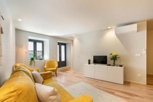 ein Wohnzimmer mit einem gelben Sofa und einem TV in der Unterkunft Sé Apartamentos - São Sebastião Apartment in Braga