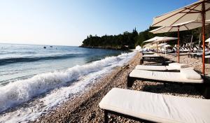 una fila di sedie a sdraio e ombrelloni in spiaggia di Emedes a Kastav (Castua)