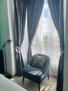 niebieskie krzesło siedzące przed oknem w obiekcie Emerald Avenue Cozy 3R3B Apartment 716 w mieście Brinchang