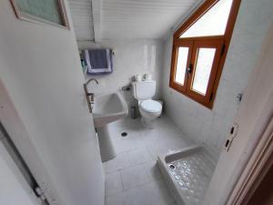 a white bathroom with a toilet and a sink at Port view Studios in Vathi