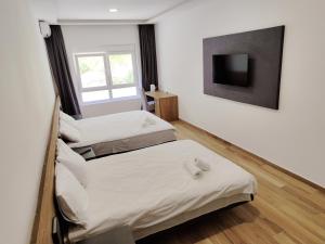 two beds in a room with a tv on the wall at H.T Hotel in Belgrade