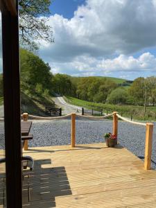 una terraza de madera con bancos en un camino de grava en Cil y Coed Luxury Pod, en Machynlleth