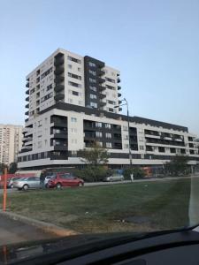 un grand bâtiment avec des voitures garées devant lui dans l'établissement Sarajevo New Apartments, à Sarajevo