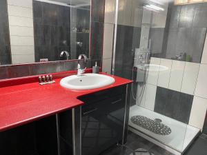 La salle de bains est pourvue d'un comptoir rouge, d'un lavabo et d'une douche. dans l'établissement Luxury Apartment in the center, à Édessa