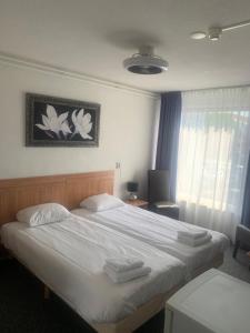 um quarto com uma cama grande e toalhas em Hotel Flevo em Zeewolde