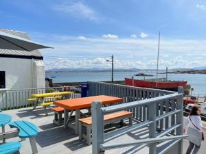 una terraza de madera con mesas, bancos y un barco en Hughie Mickey Dan's B&B, 