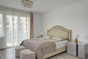 ein weißes Schlafzimmer mit einem großen Bett und einem Kronleuchter in der Unterkunft Vision Apartments Budapest in Budapest