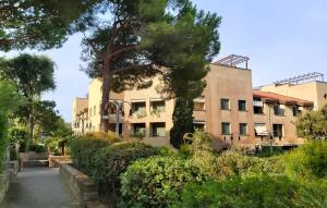 un edificio con árboles frente a una calle en Punta Ala Boboli Apartment, en Punta Ala