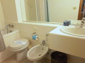 Baño blanco con aseo y lavamanos en Punta Ala Boboli Apartment, en Punta Ala